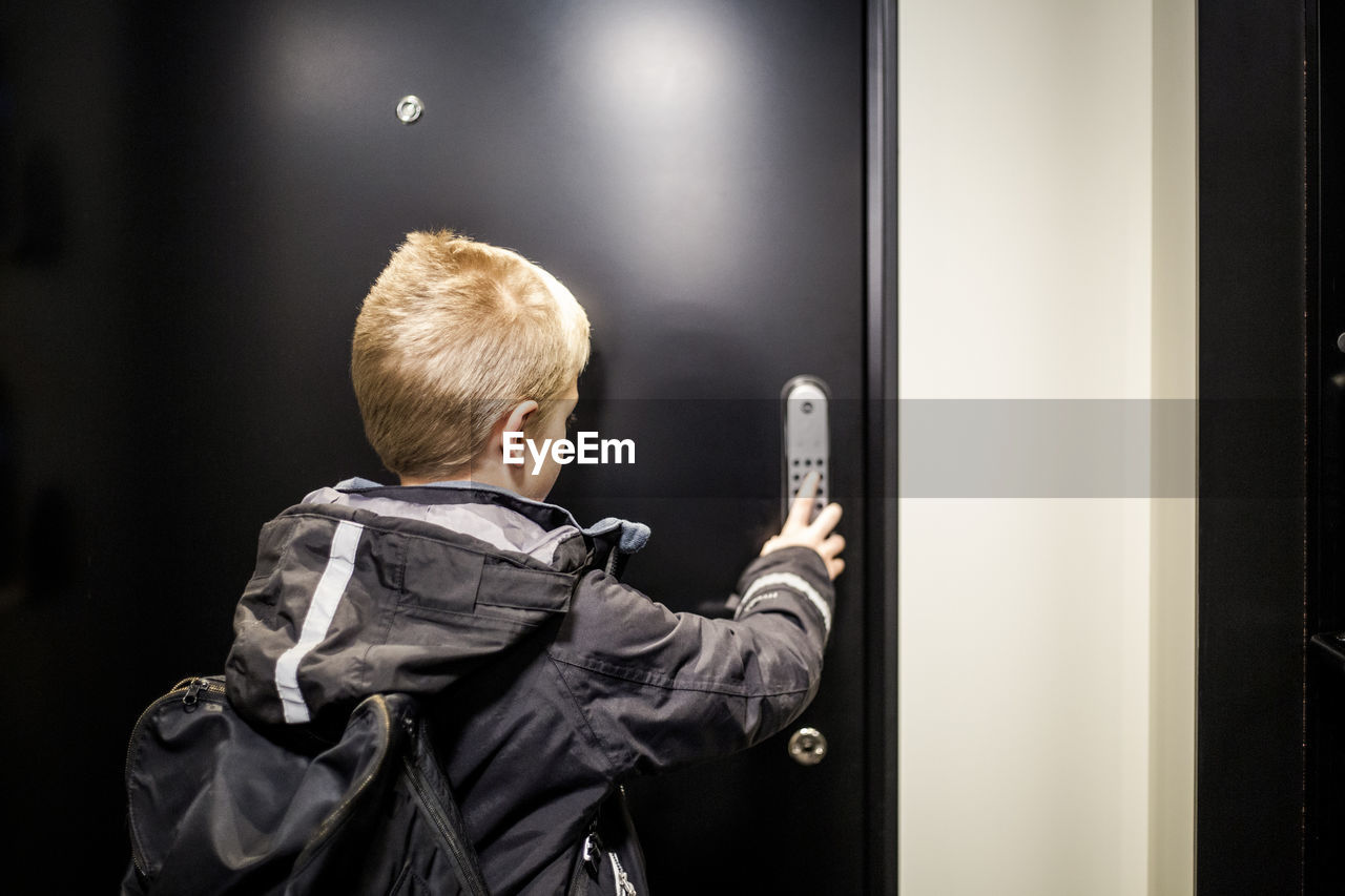 Boy unlocking combination security code on house door