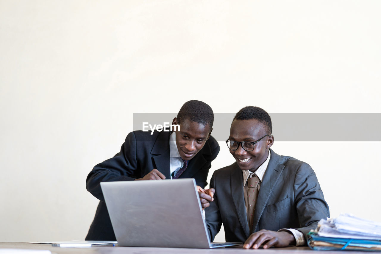 Male colleagues discussing over laptop on table against white background