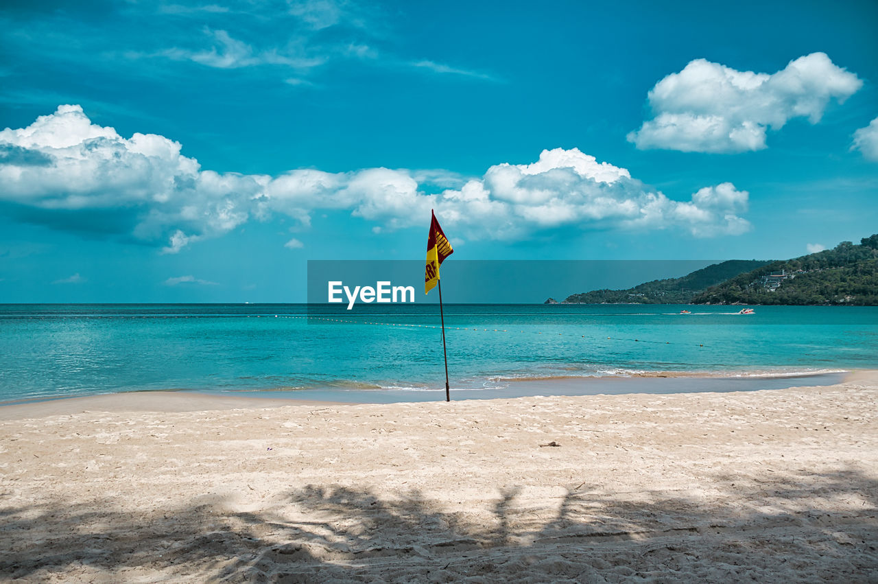 Empty, calm sandy patong beach in phuket with turquoise blue clear water and cirrus cloudy sky