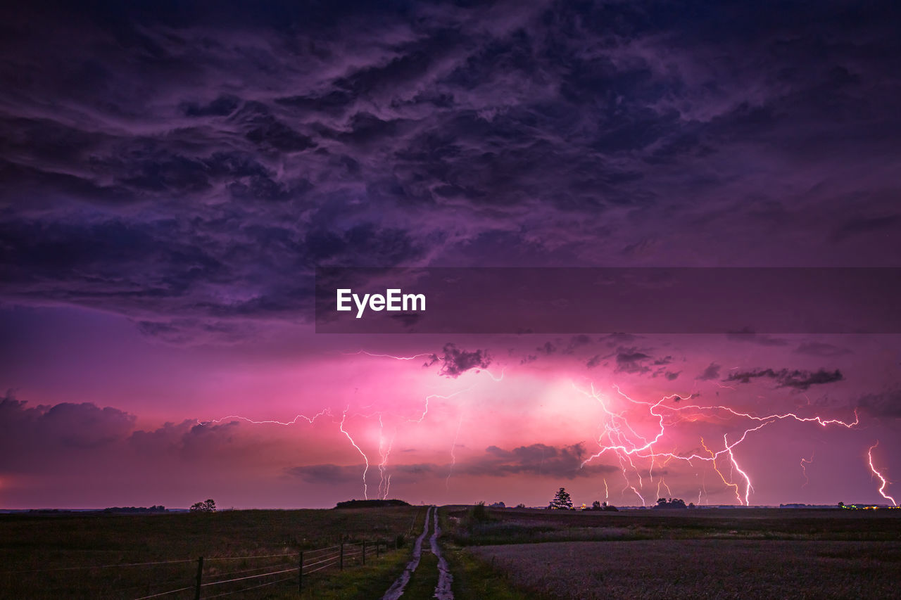 Thunderstorms on land against sky at dusk