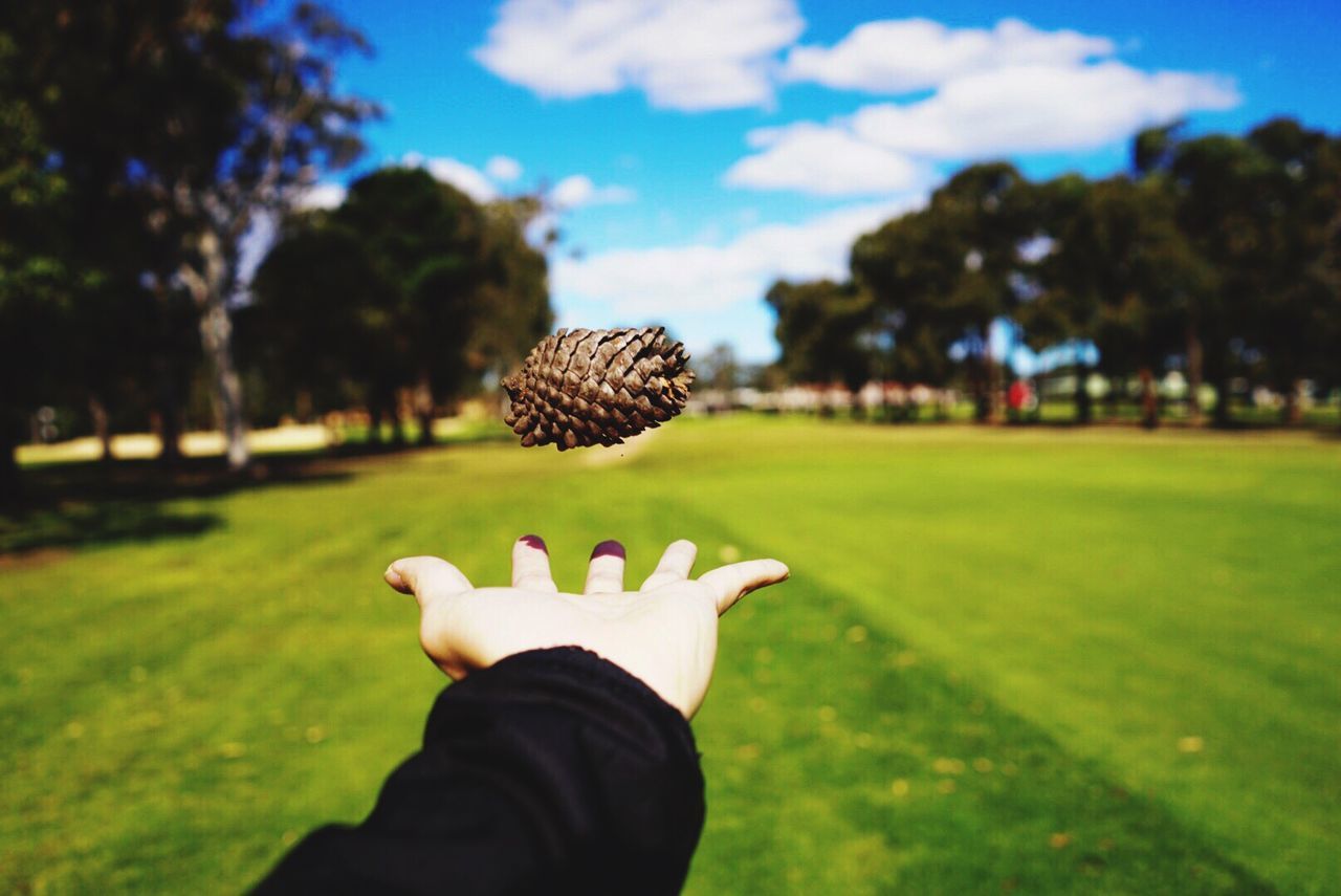 CLOSE-UP OF HAND HOLDING BALL ON FIELD