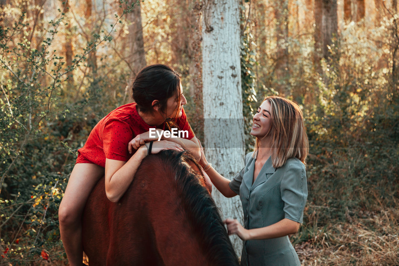 Woman sitting on horse while standing with friend