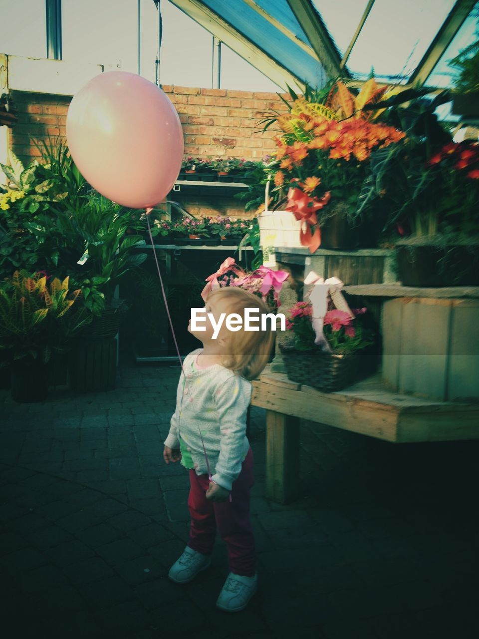 Girl with balloon standing against plants