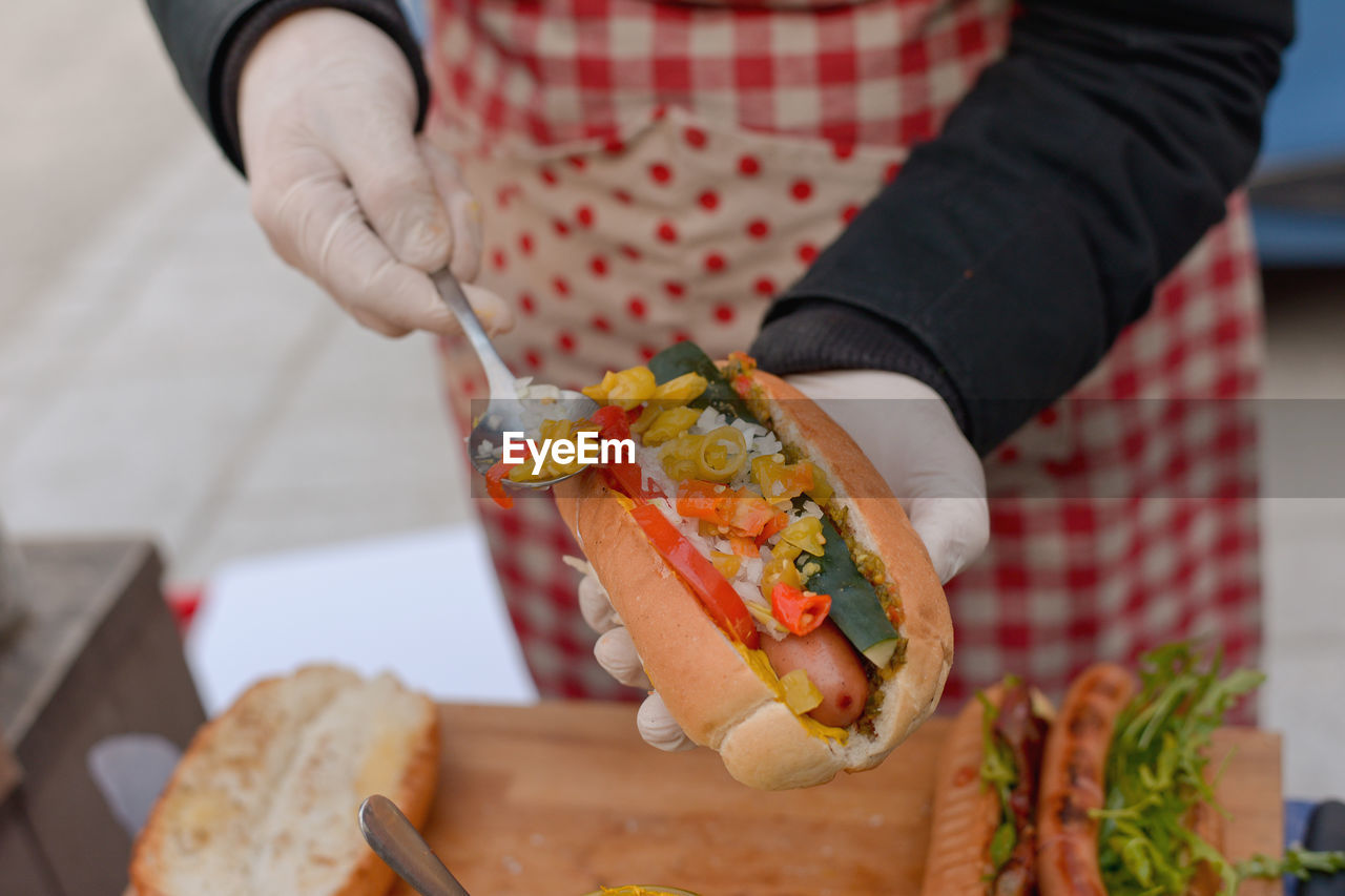 Midsection of man preparing hot dog at home