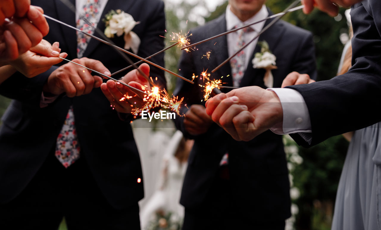 midsection of bride and bridegroom holding bouquet