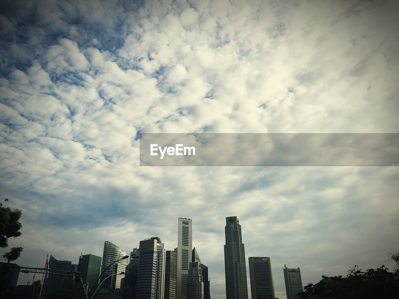 LOW ANGLE VIEW OF MODERN CITY AGAINST CLOUDY SKY