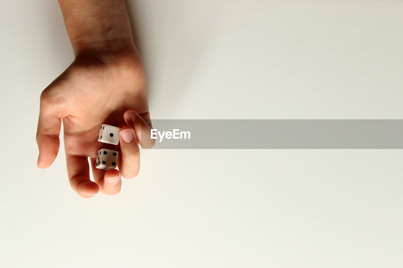 Cropped hand of man rolling dices over white background