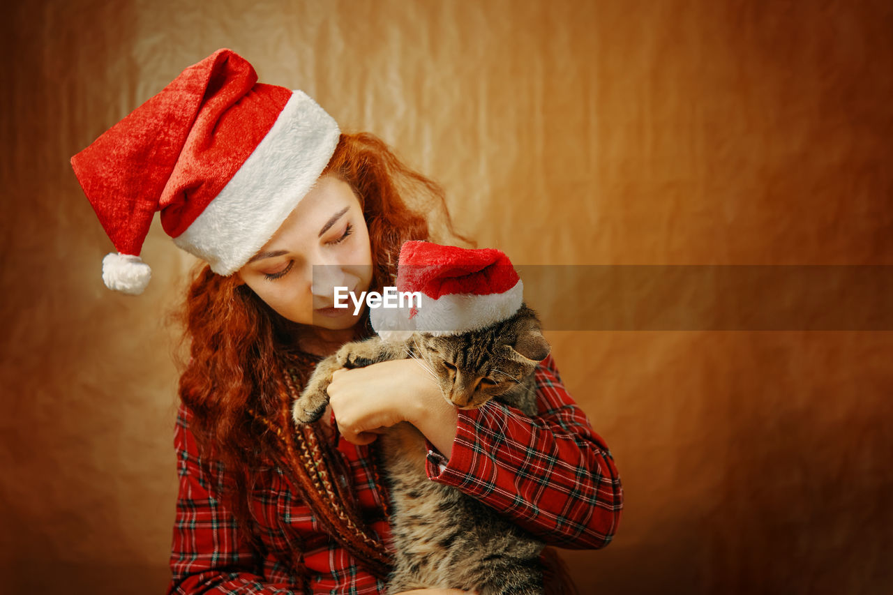 PORTRAIT OF YOUNG WOMAN IN HAT WITH CHRISTMAS TREE