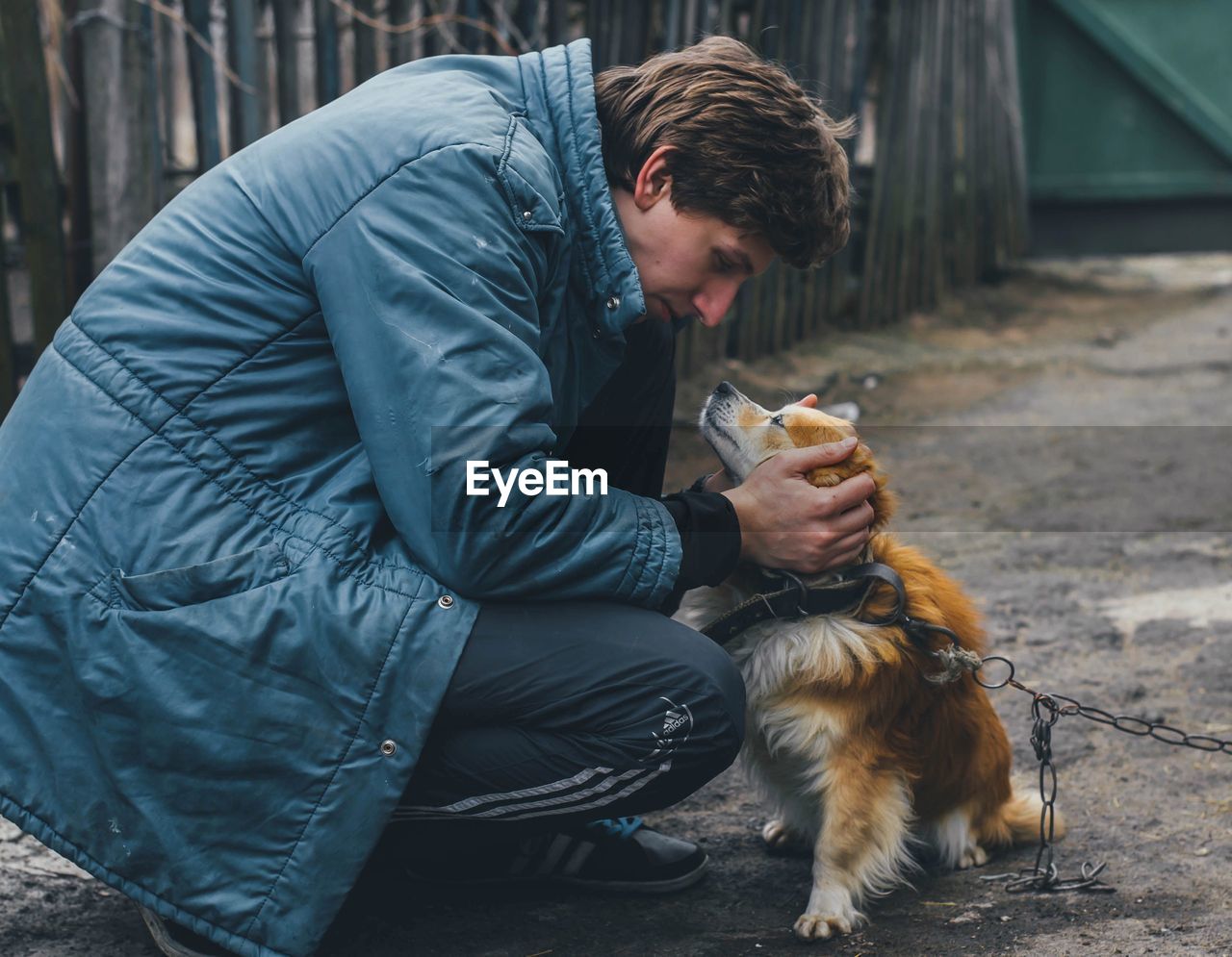 FULL LENGTH OF YOUNG MAN HOLDING DOG AT CAMERA