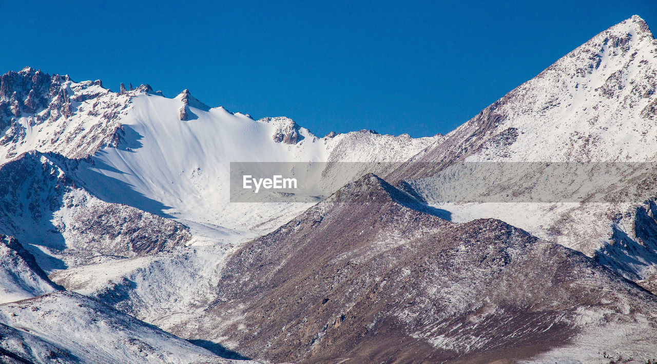 AERIAL VIEW OF SNOWCAPPED MOUNTAIN AGAINST BLUE SKY