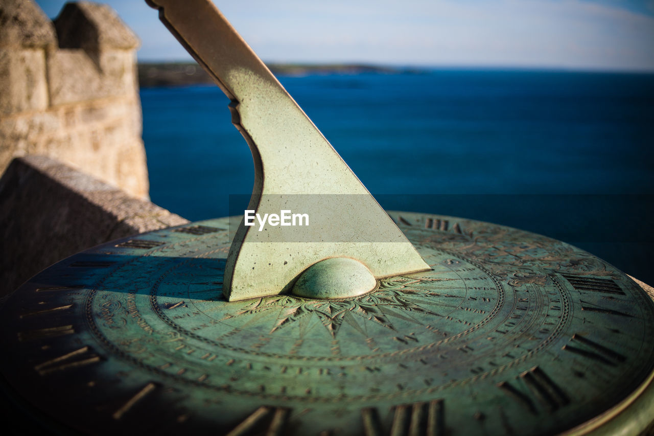 Detail shot of sundial against calm sea
