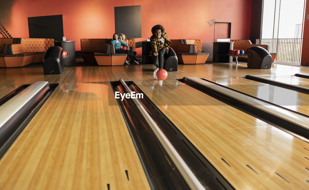 Young man playing throwing ball at bowling alley