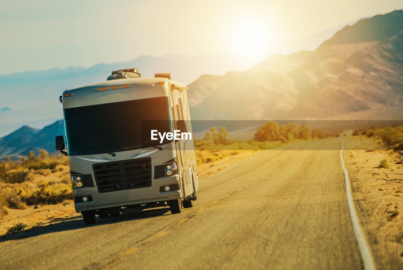 Semi-truck on road against sky during sunset