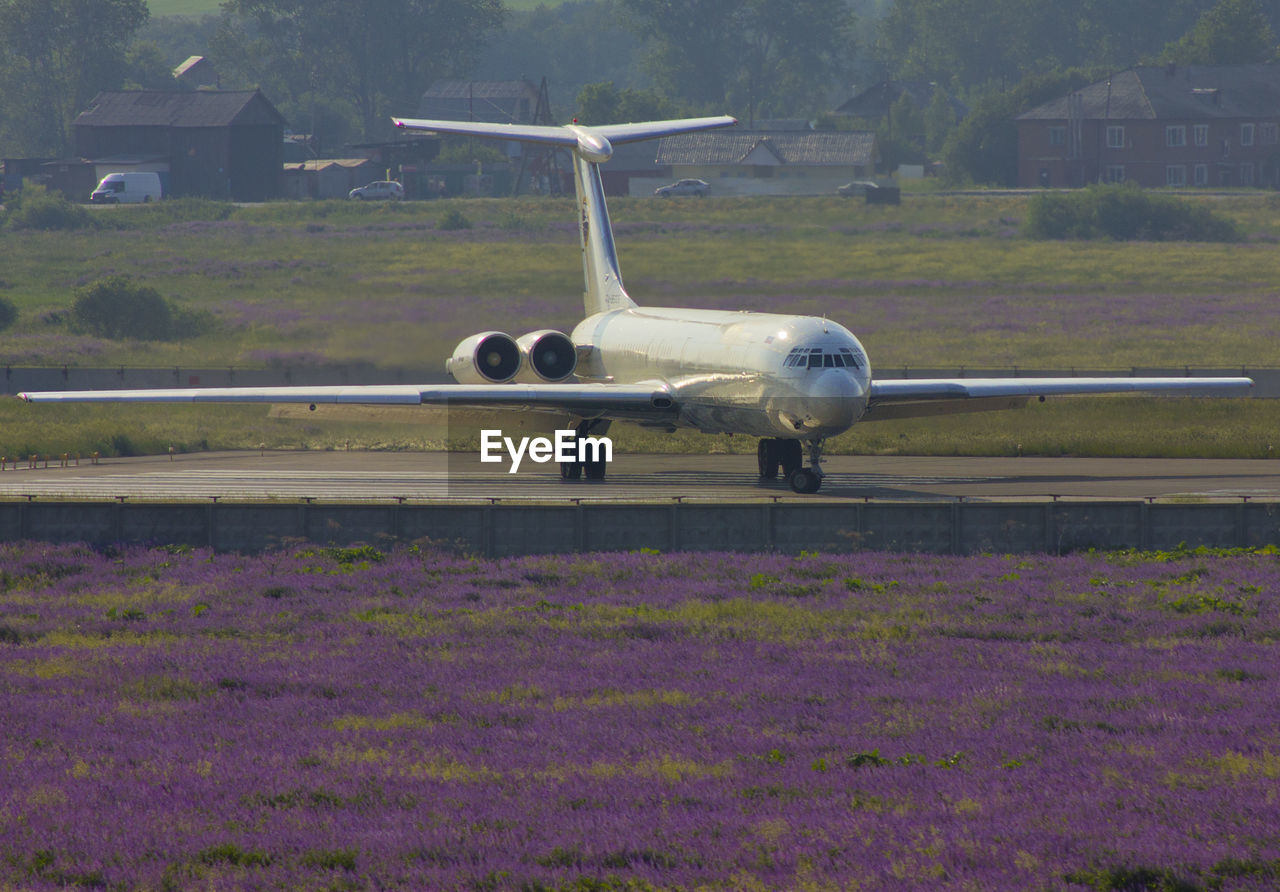 VIEW OF AIRPLANE FLYING OVER FIELD