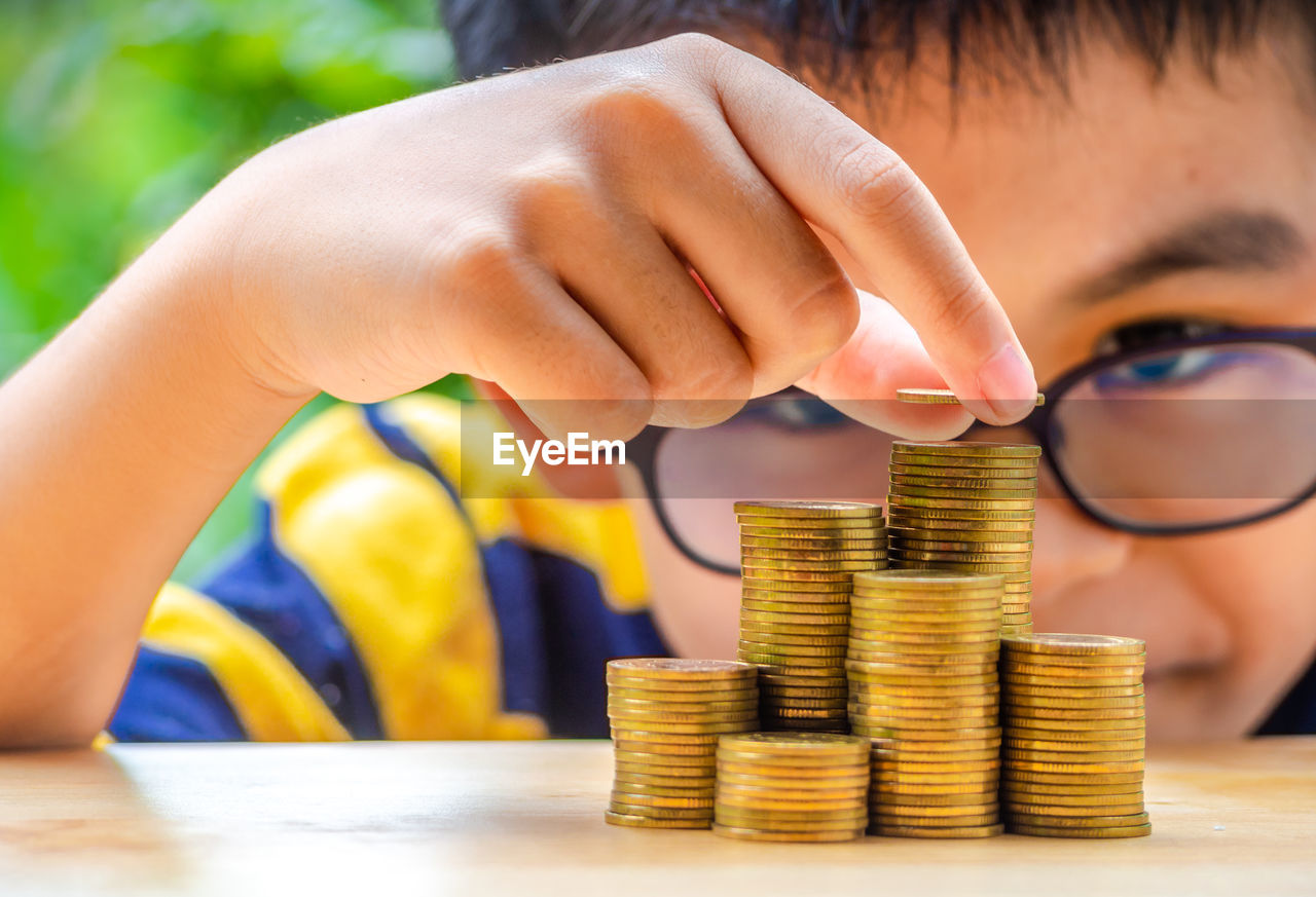 Close-up of boy stacking coins on table