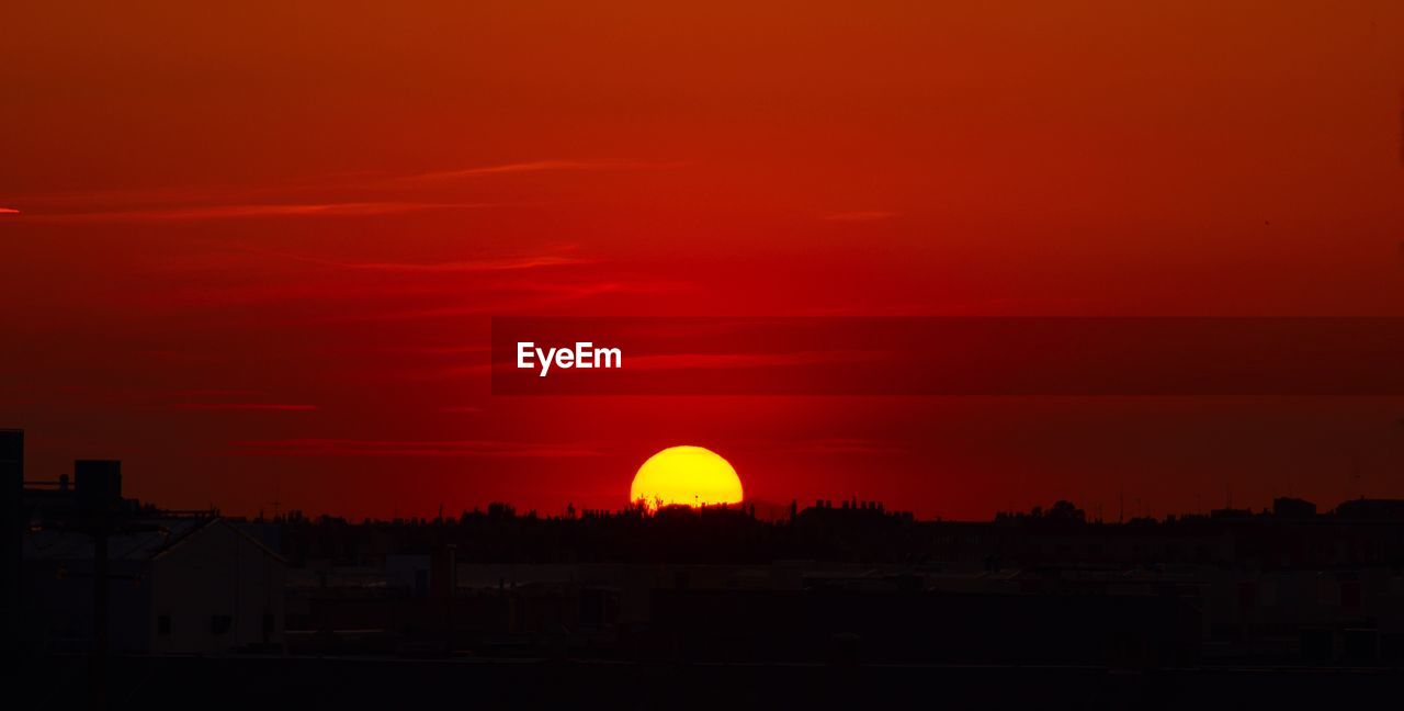 Silhouette buildings against orange sky