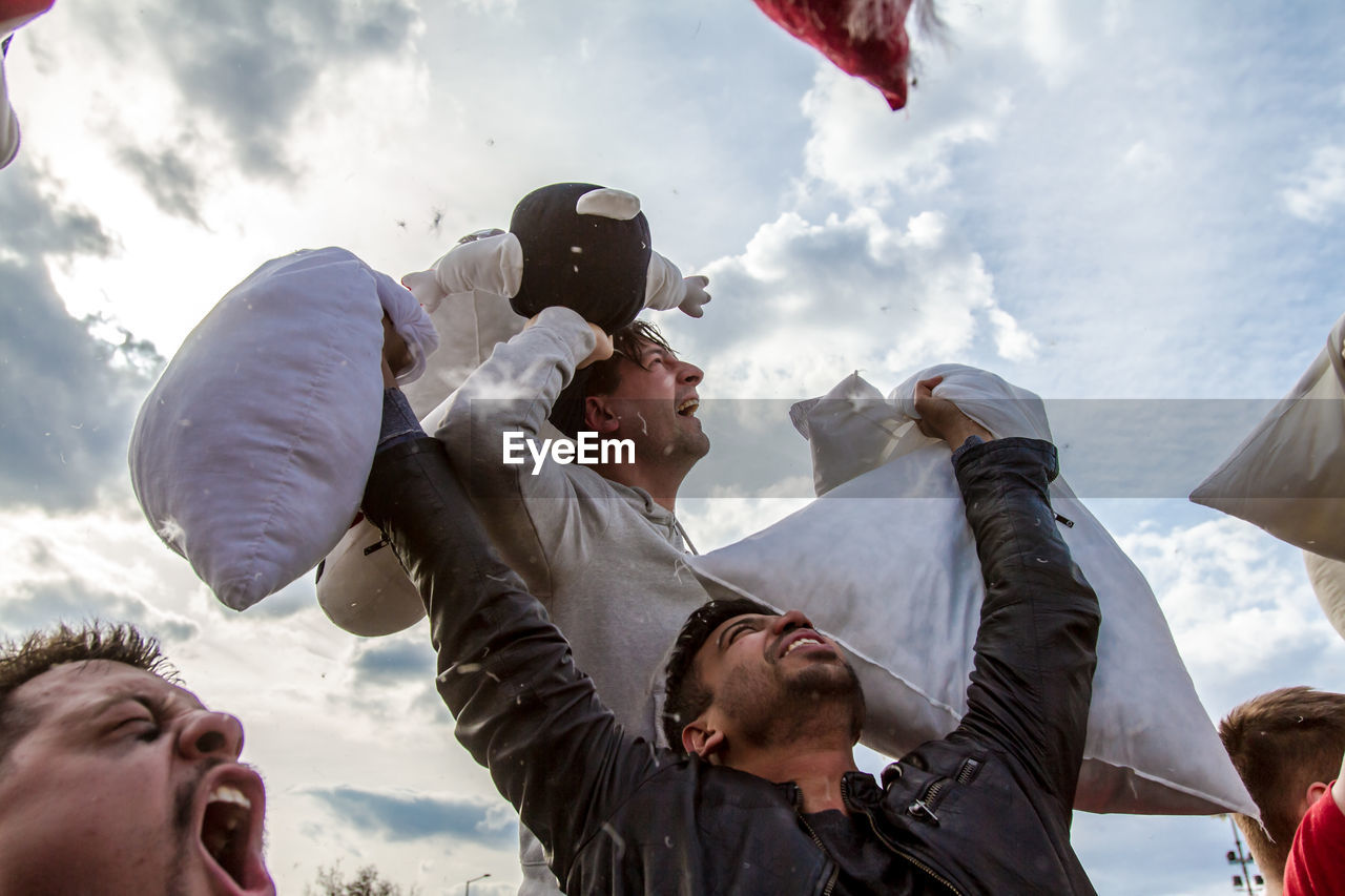 LOW ANGLE VIEW OF PEOPLE AGAINST CLOUDY SKY