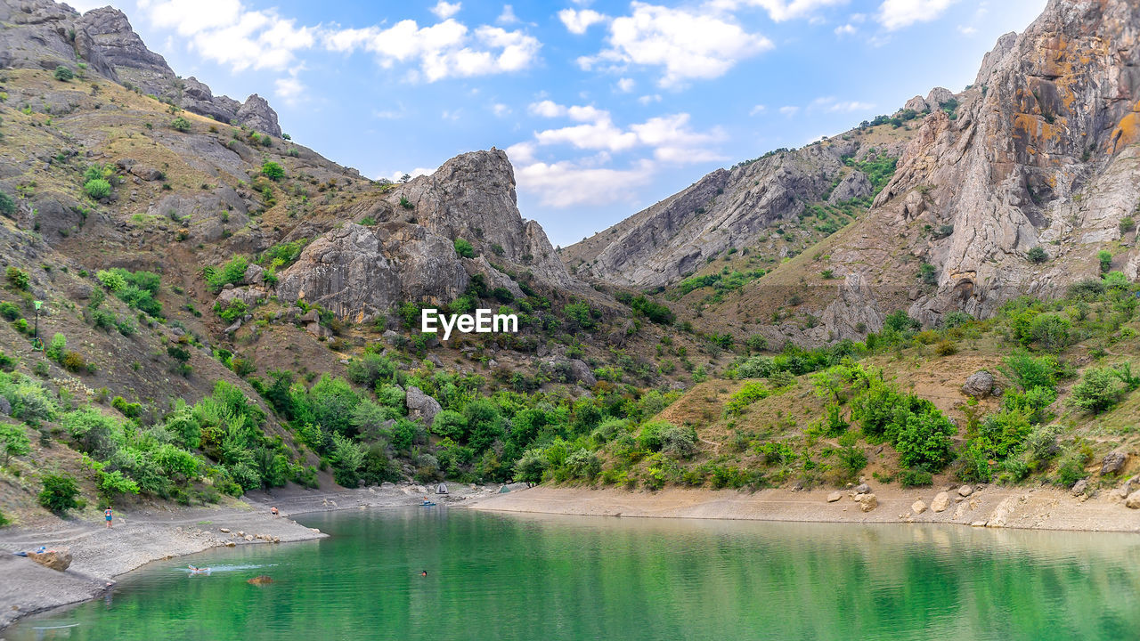 SCENIC VIEW OF MOUNTAIN BY LAKE AGAINST SKY