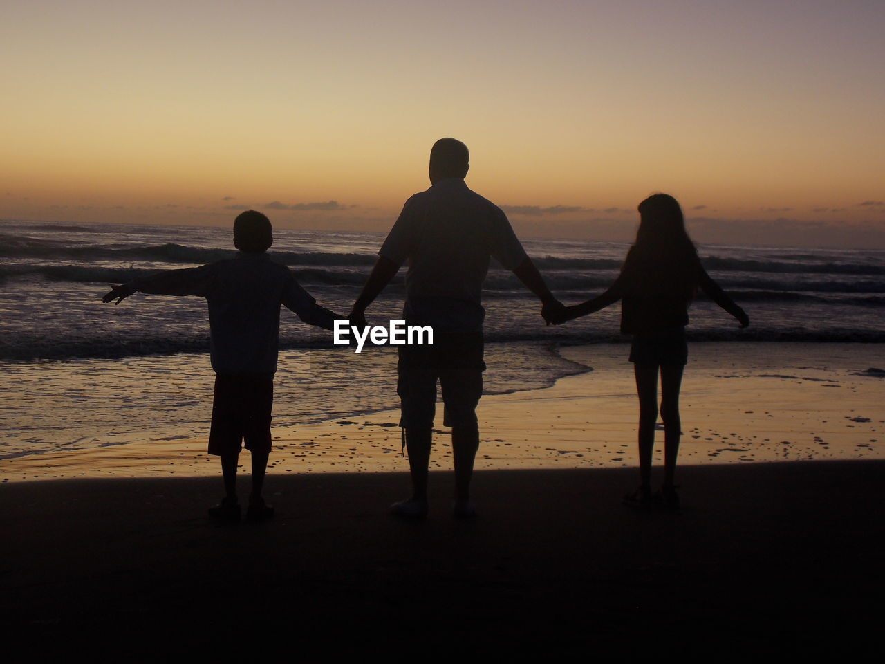 Silhouette of people on beach at sunset