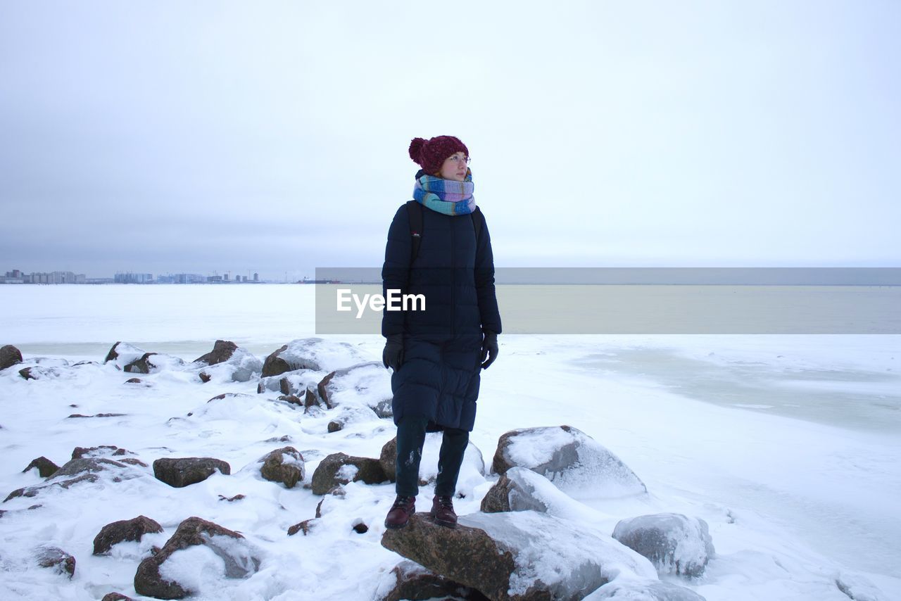 Full length of woman standing on rock during winter