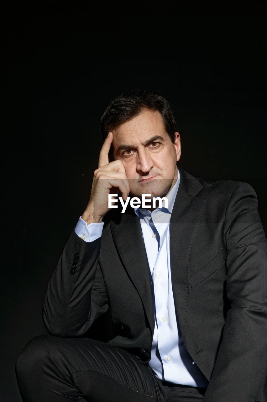 MID ADULT MAN SITTING IN FRONT OF FACE