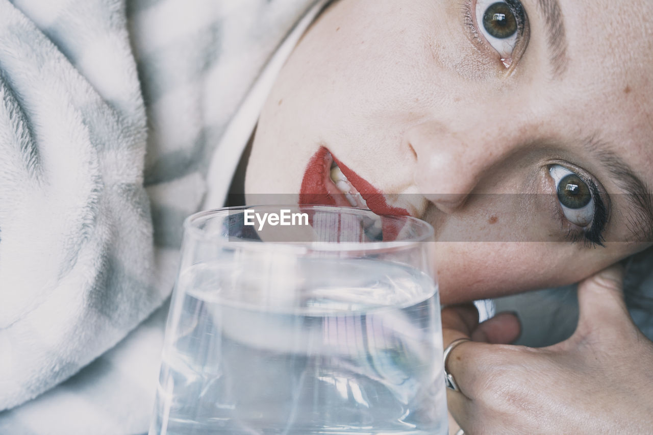 Close-up portrait of woman holding glass of water