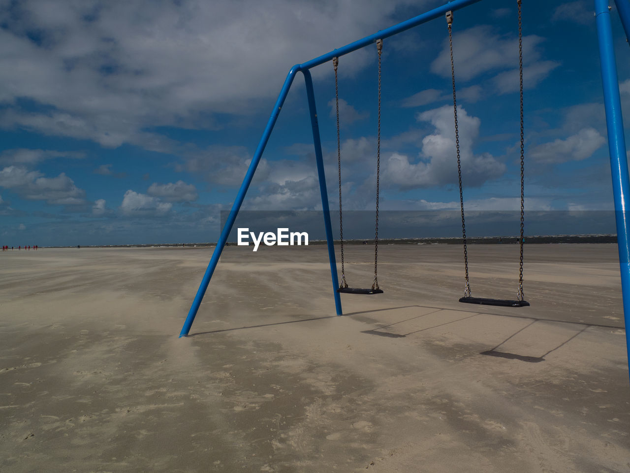 View of swing on beach against cloudy sky