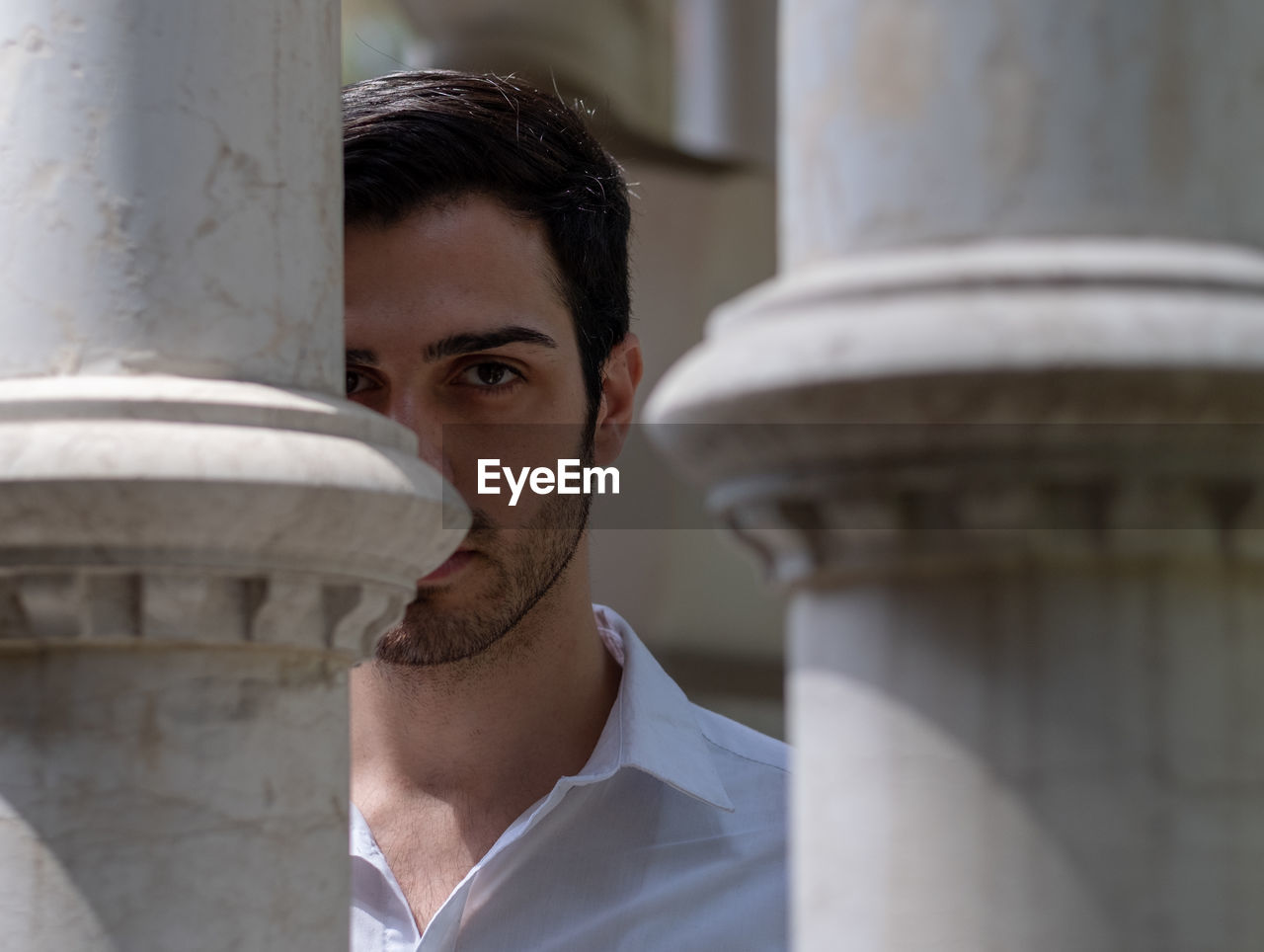 Portrait of young man seen through columns