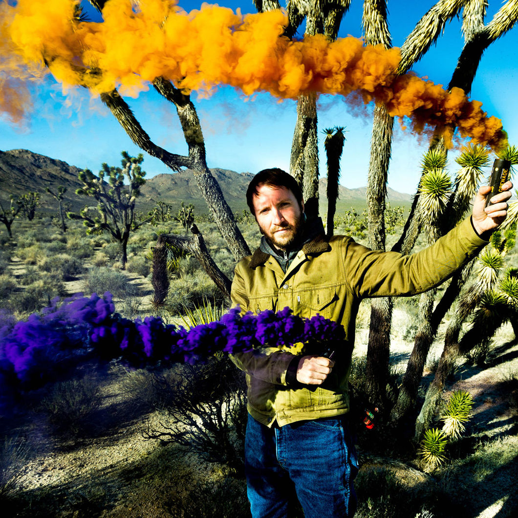 Portrait of man holding smoke bomb at field