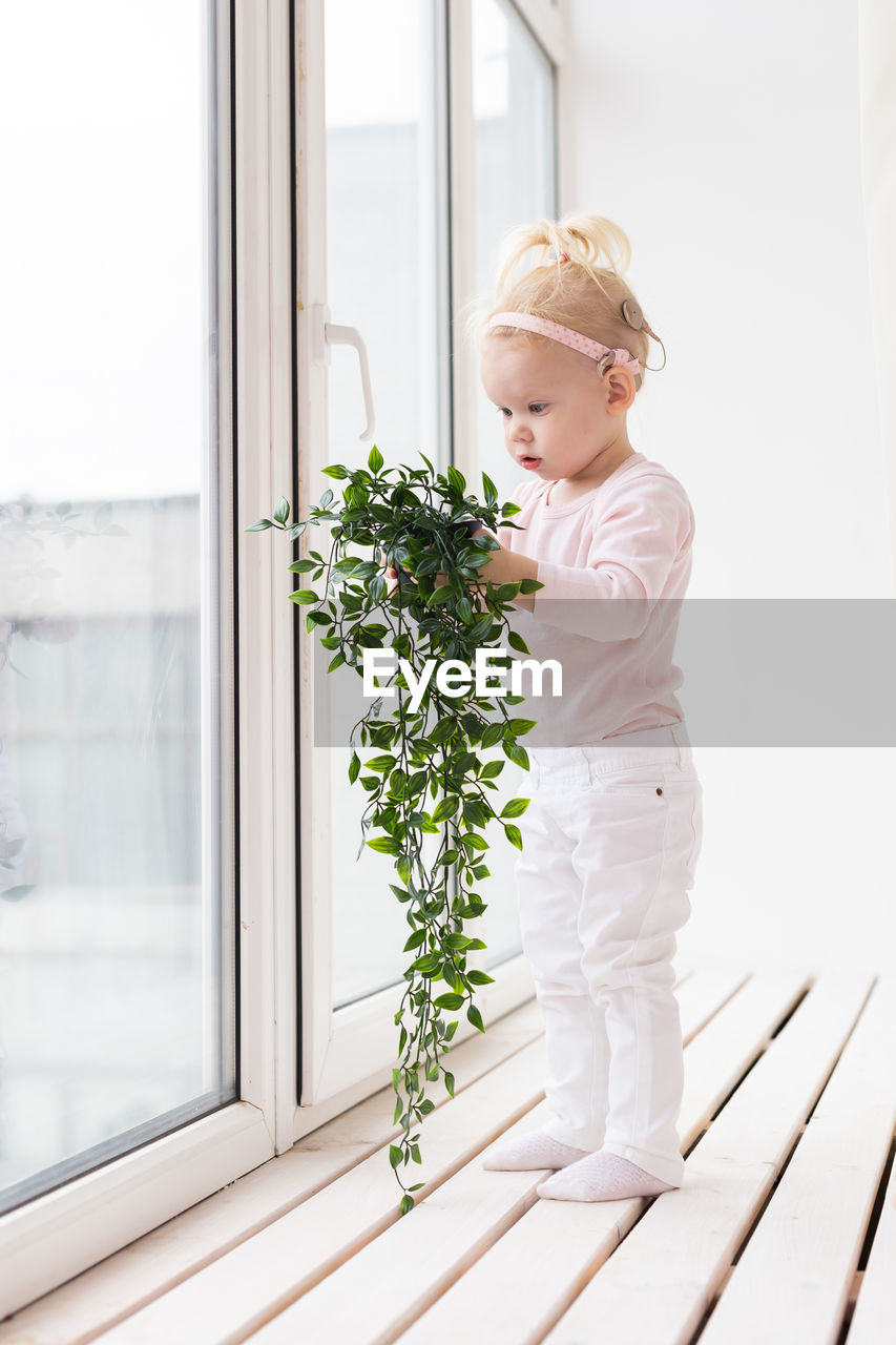 portrait of young woman standing against window