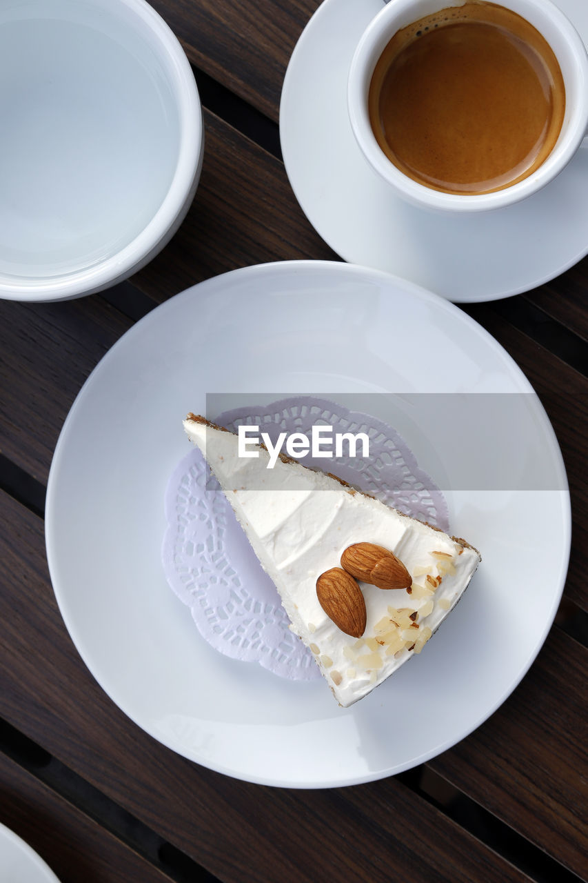 An almond cake in a white dish with a coffee cup, a wooden background.