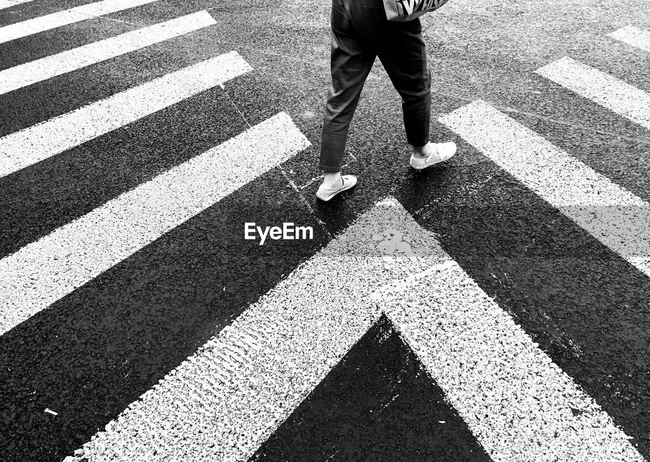 Low section of woman walking on zebra crossing