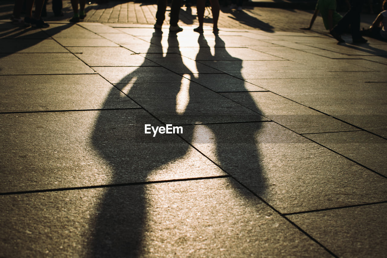 Shadow of people walking on footpath during sunset