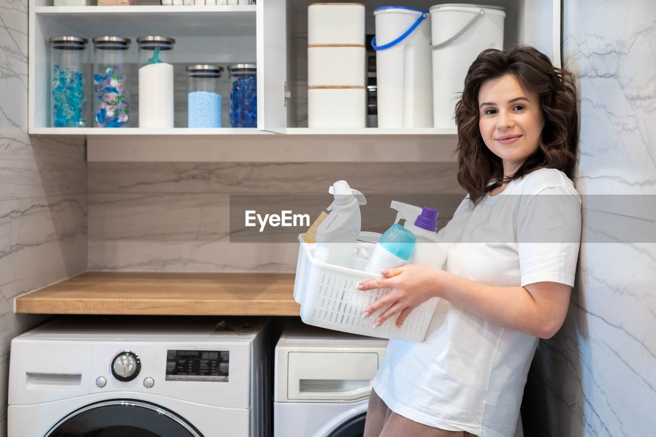 portrait of smiling young woman drinking water while standing in laboratory