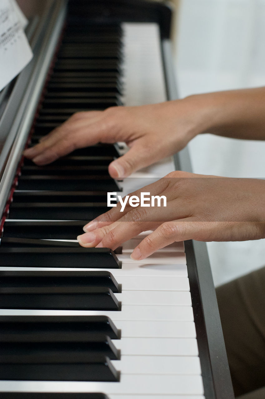 Cropped hands of woman playing piano