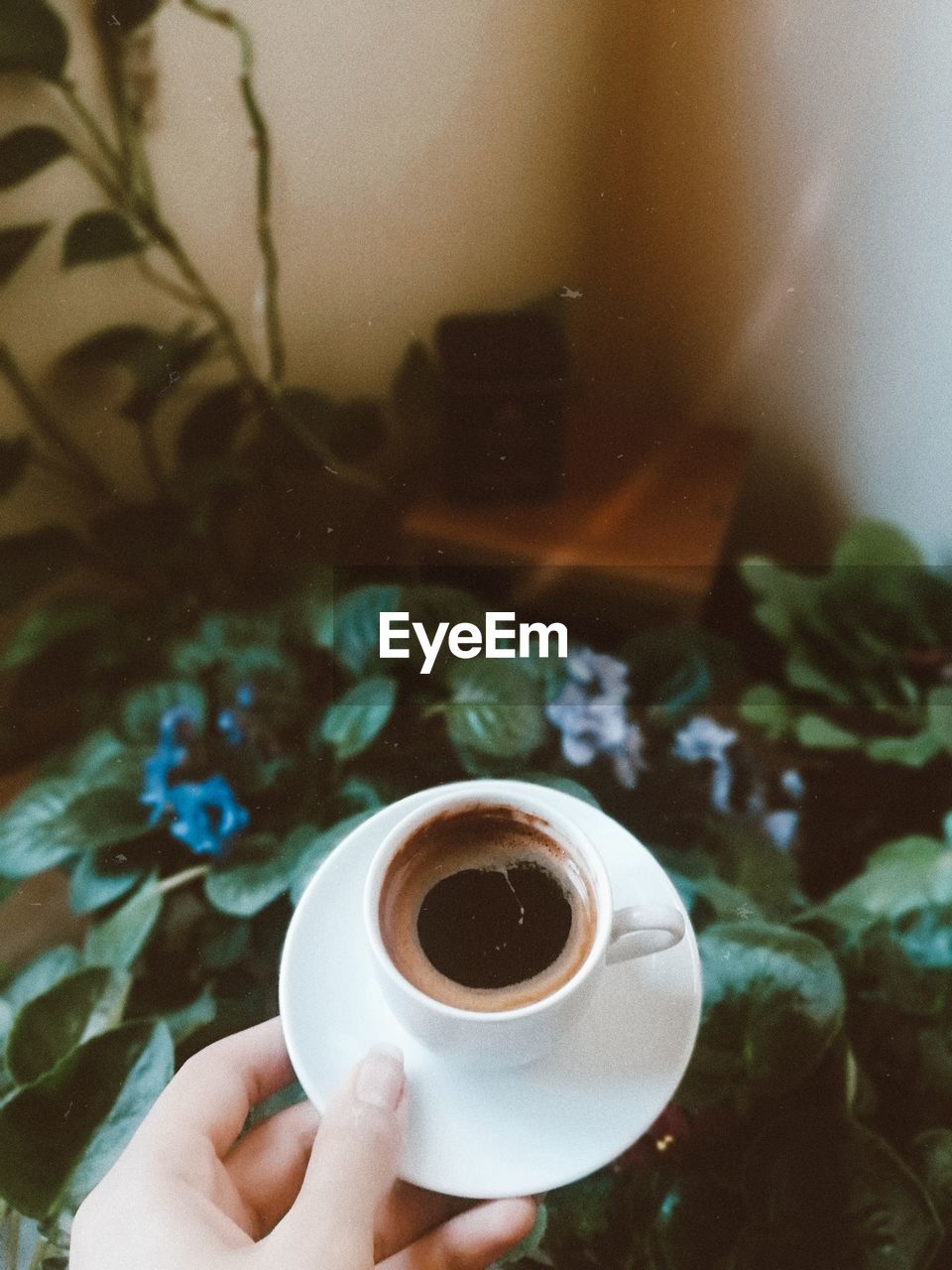 CLOSE-UP OF HAND HOLDING COFFEE CUP WITH SPOON