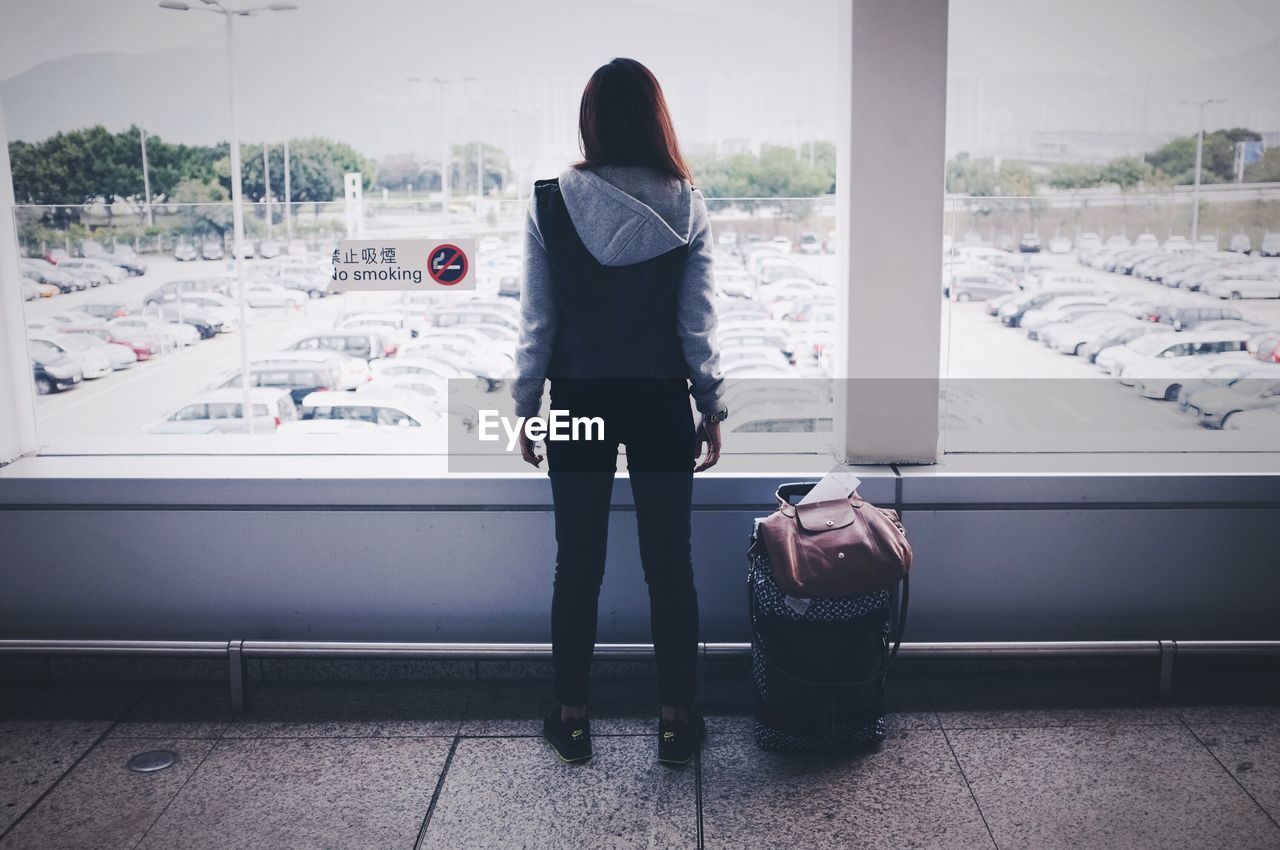 Rear view of woman standing by window