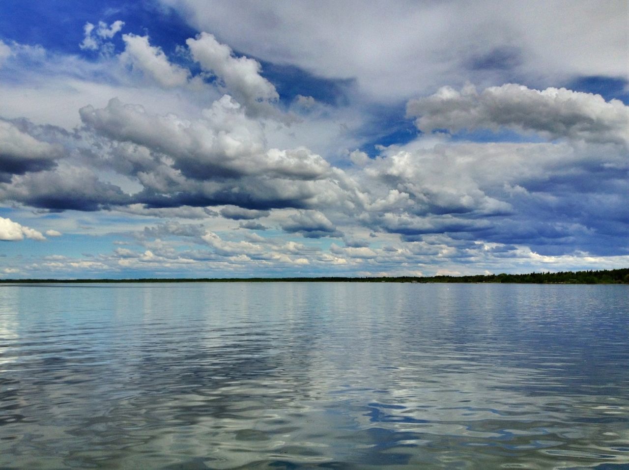 Scenic view of lake by trees against cloudy sky