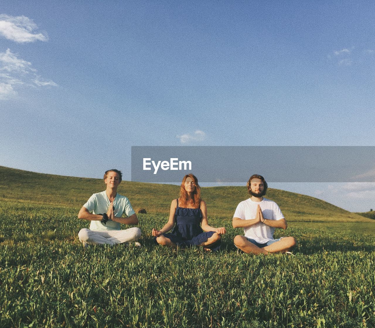 Friends practicing yoga on grassy field