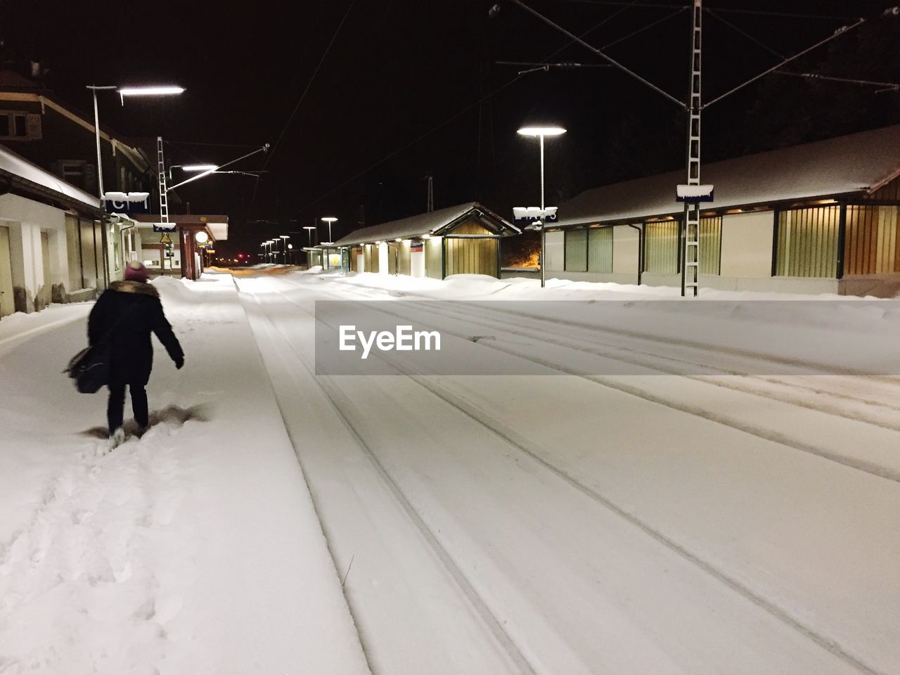 Snow covered road amidst buildings at night