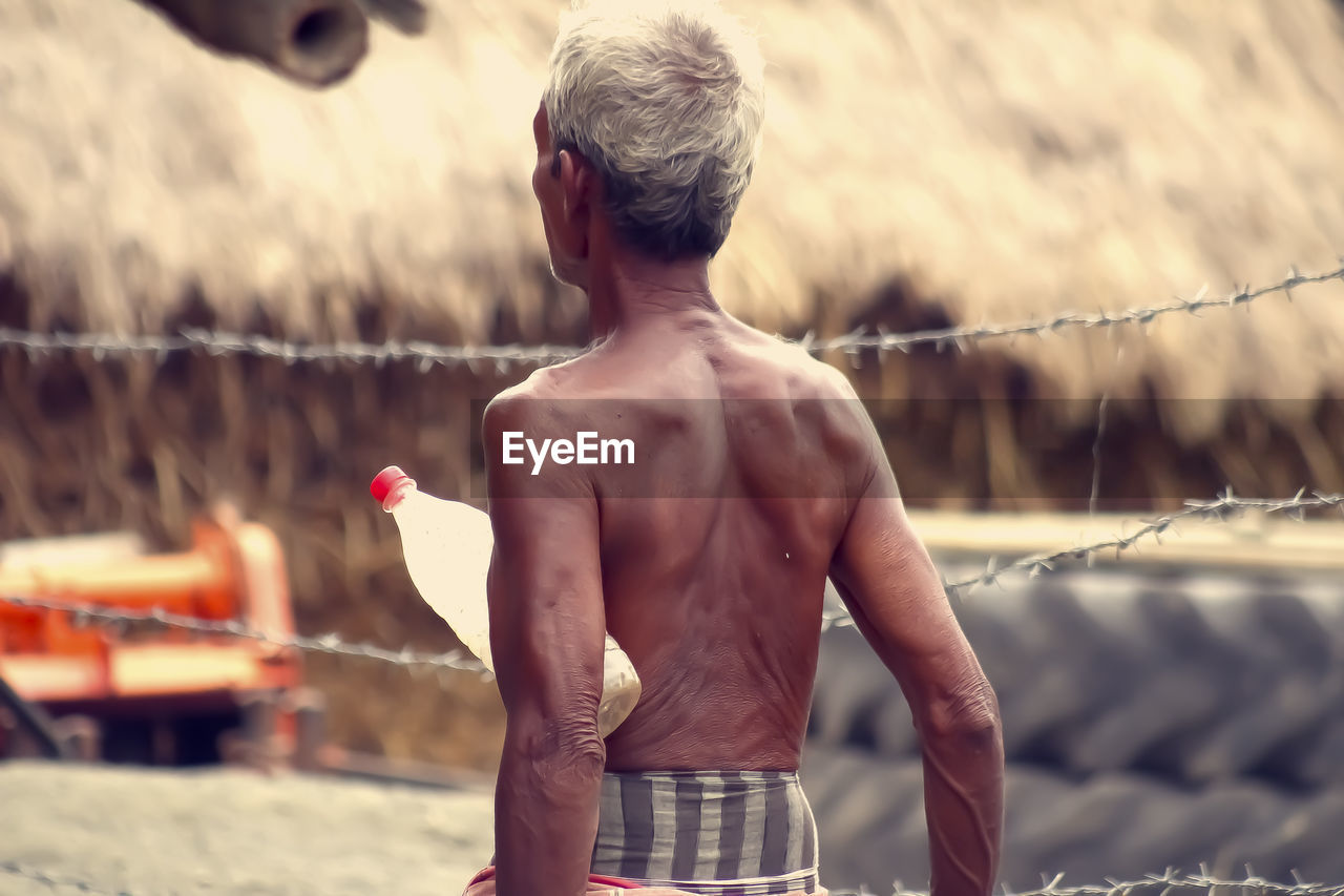 side view of shirtless man standing on railing