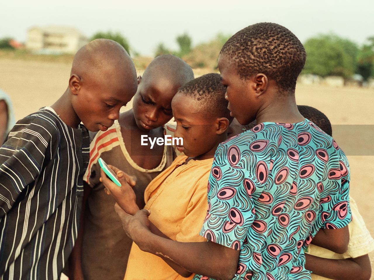 Teenage friends using mobile phone while standing at field