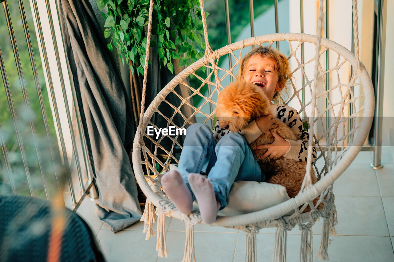 Portrait of little girl, dog in hammock