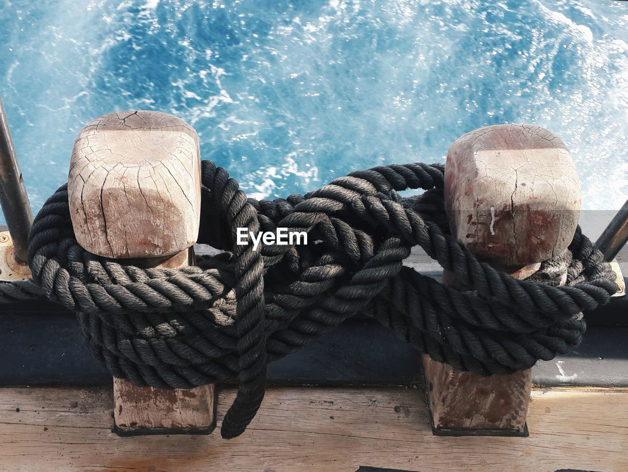 High angle view of black ropes tied on boat bollards over sea