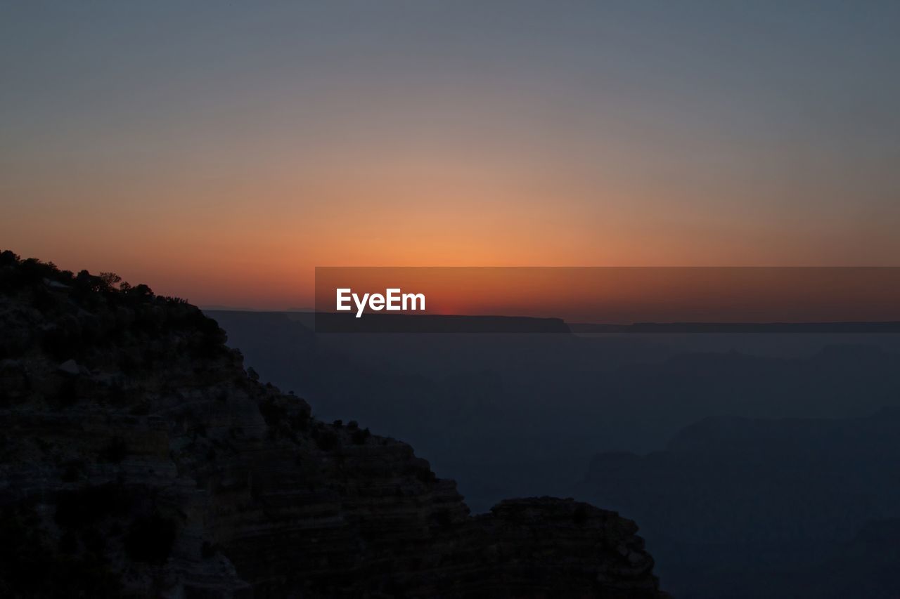 SCENIC VIEW OF SILHOUETTE MOUNTAIN AGAINST ORANGE SKY