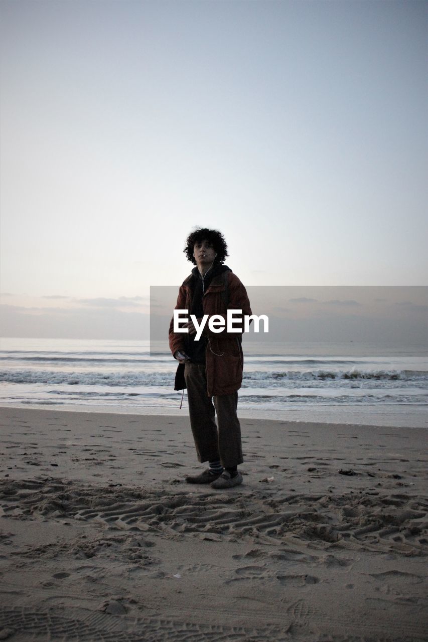 Portrait of man standing at beach against sky