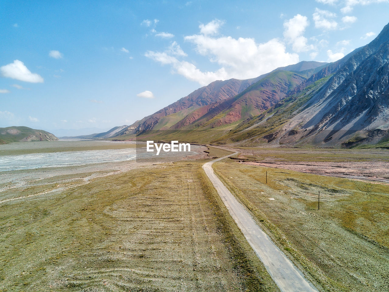 Road leading towards mountains against sky