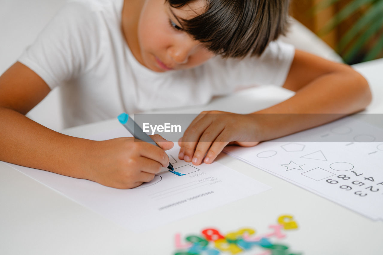 Child coloring shapes in a preschool assessment test.