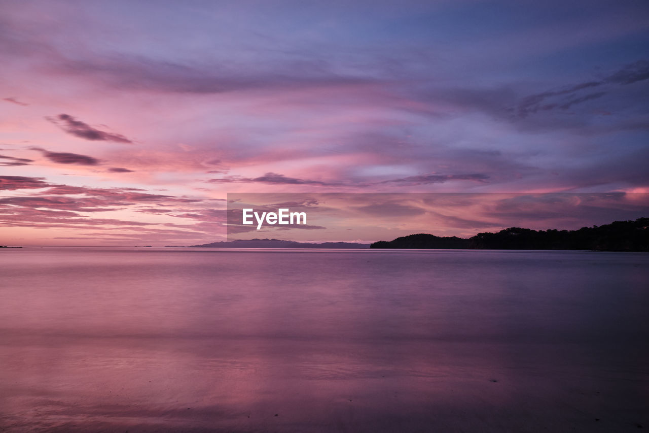 Scenic view of sea against dramatic sky during sunset