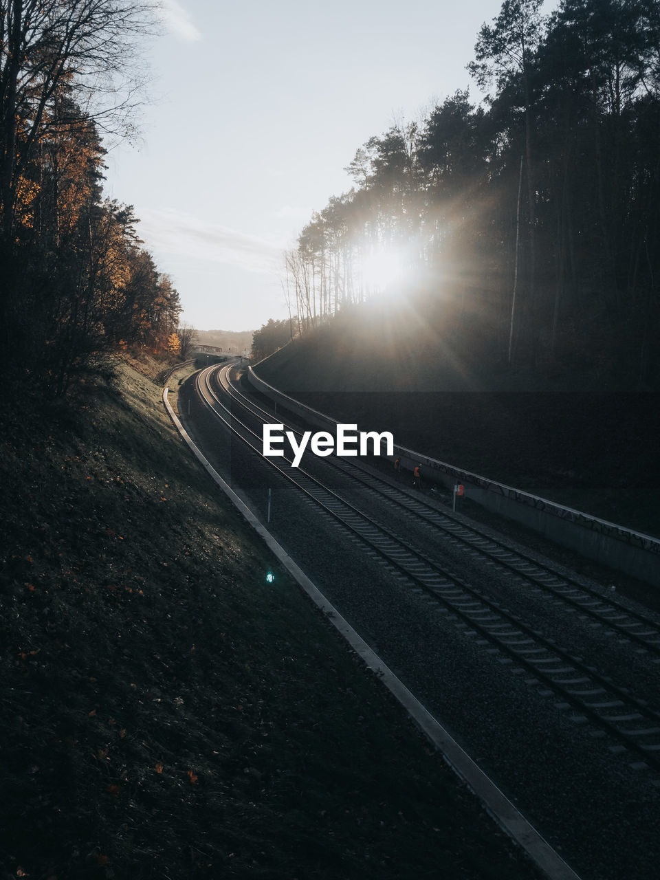 Railroad tracks by road against sky during sunset